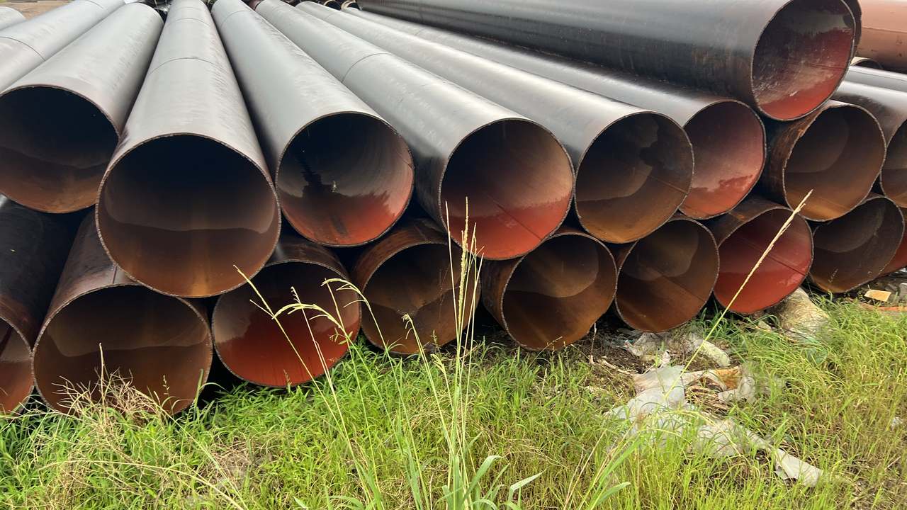 A stack of large-diameter steel line pipe in the yard