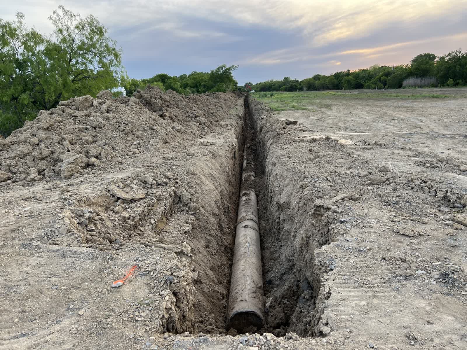 Exposed line pipe running the length of an open ditch across a right-of-way